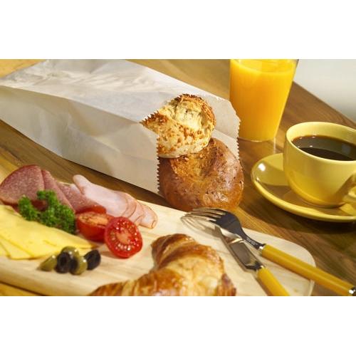 A breakfast buffet with cheese slices, cold cuts, tomatoes, olives, a croissant, rolls in a PAPSTAR 1000 paper folding bag from PAPSTAR GmbH, black coffee, orange juice, and cutlery, arranged on a wooden table.