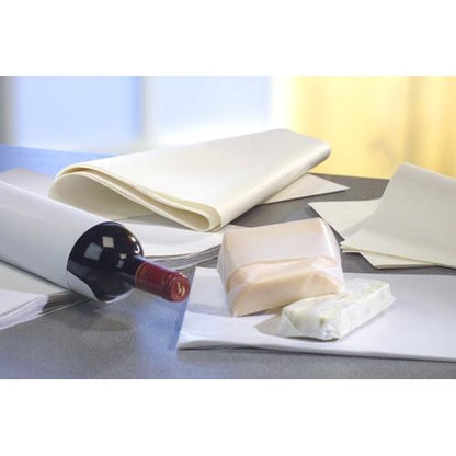 On a gray background, 10 kg white cellulose wrapping papers from PAPSTAR GmbH can be seen, wrapping a wine bottle, a small package, and cheese alongside several sheets of the environmentally friendly paper.