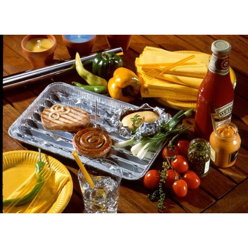 Auf einer Tischplatte werden 5 Starpak-Grillschalen präsentiert, Alu-Tabletts von Starpak mit einem Burger-Patty, einer Zimtschnecke, einer Ofenkartoffel in Folie und Beilagen wie Gemüse, Soßen, Tellern, Servietten, Kerzen und einem Getränk – ideal für jede Grillparty.