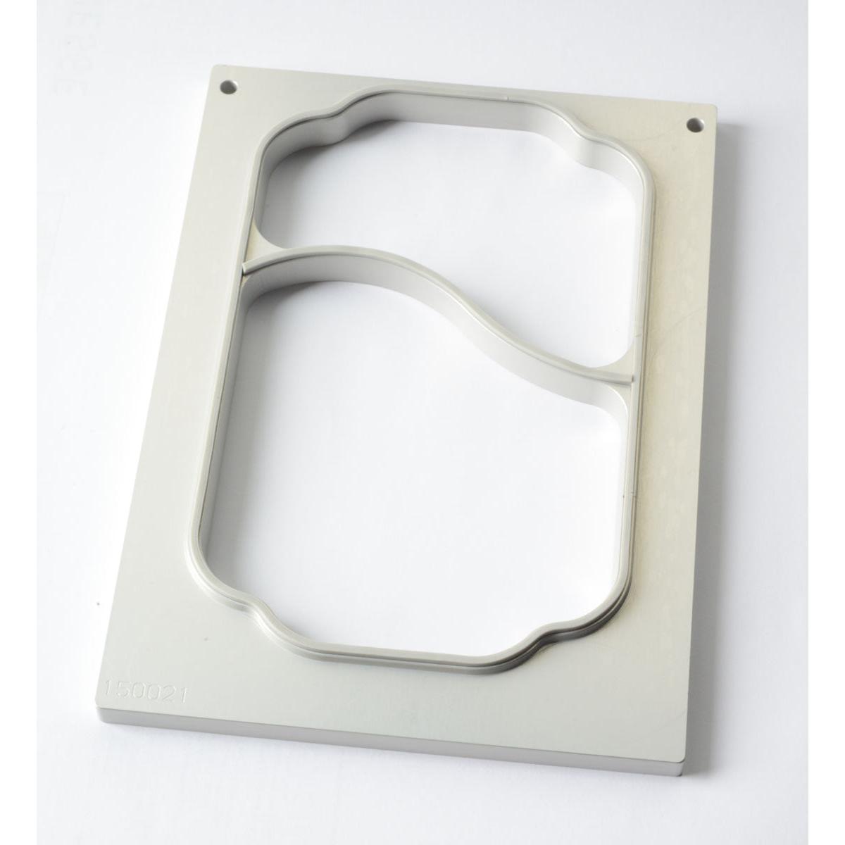 Eine Kassette DF10/20 2-comp für PP-Schale Take Away 700/400 ml von Duni GmbH, bestehend aus einer rechteckigen Metallplatte mit zwei separaten gebogenen Ausschnitten, die durch einen diagonalen Steg getrennt sind, wird auf einer weißen Fläche dargestellt. Verpackung (1 Stück).