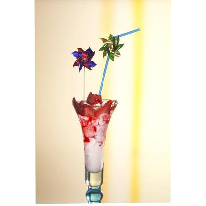 A tall glass with a pink-white frozen drink, garnished with strawberry pieces and two PAPSTAR 100 decoration picks from PAPSTAR GmbH and a blue straw, on a light background with a yellow stripe.
