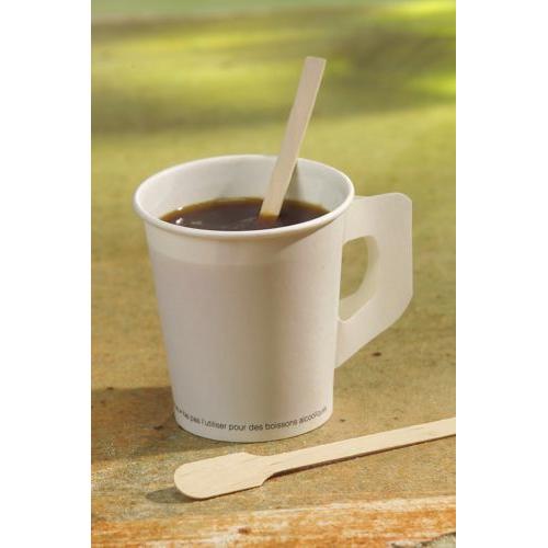 Auf einer Fläche steht ein weißer Pappbecher mit schwarzem Kaffee, darin ein PAPSTAR „pure“ Rührstäbchen der PAPSTAR GmbH, daneben ein weiteres natürlich helles Rührstäbchen vor einem sanft verschwommenen Hintergrund.