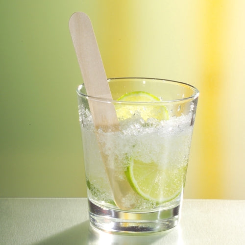 Ein klares Glas mit zerstoßenem Eis und Limette, versehen mit einem PAPSTAR 100 Getränke-Quirle, Holz 15 cm „Caipirinha“-Rührstab der PAPSTAR GmbH, auf gelbgrünem Hintergrund für eine erfrischende Optik.