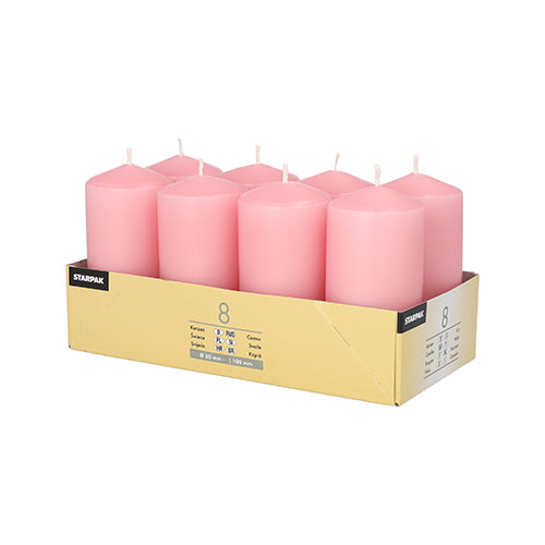A cardboard tray contains 8 pink Starpak pillar candles (Ø 50 mm · 100 mm), arranged in two rows of four each. The light yellow packaging with product information on the front and back creates a cozy atmosphere.