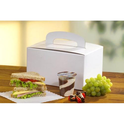 A PAPSTAR 20 lunch box made of environmentally friendly cardboard (12.5x15.5x22.5 cm) with a carrying handle from PAPSTAR GmbH is on a wooden table next to a sandwich, chocolate-vanilla pudding, two pralines, and green grapes.