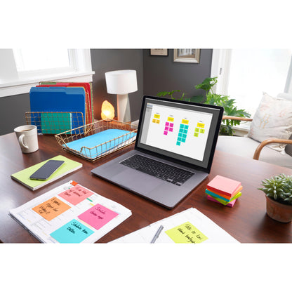 A home office desk with a laptop with digital sticky notes, colored folders, a smartphone, a lamp, papers with handwritten notes, a potted plant, and 3M Deutschland GmbH Post-it® Notes (76x127 mm, 100 sheets/block, 6 blocks/pack, 100% PEFC).