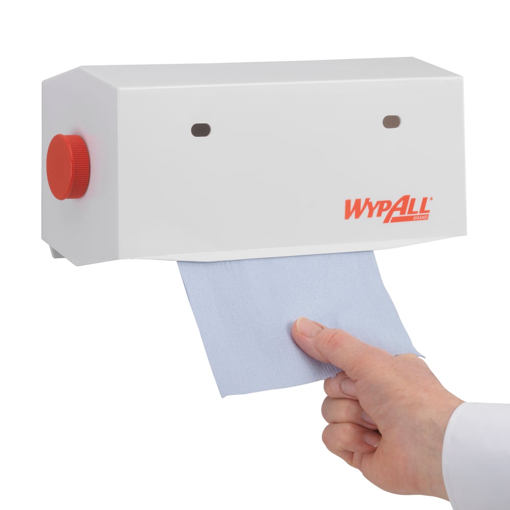 Eine Hand zieht ein blaues Papierhandtuch aus einem wandmontierten, weißen WypAll® Wischtuch-Spender - Kleinrollen (25 cm) der Kimberly-Clark GmbH mit rotem Knauf.