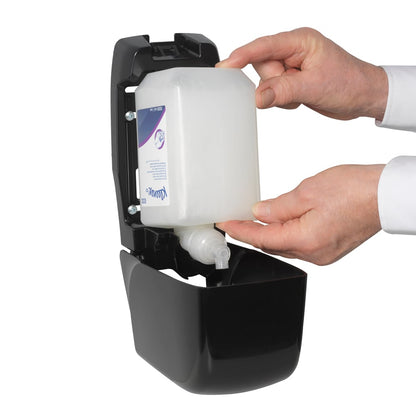 Eine Person führt eine Kleenex® Haar- und Körpershampoo 1L Kassette von Kimberly-Clark GmbH in einen offenen schwarzen Wandspender ein und benutzt dabei beide Hände, um eine sanfte Pflege und effektive Reinigung zu gewährleisten.