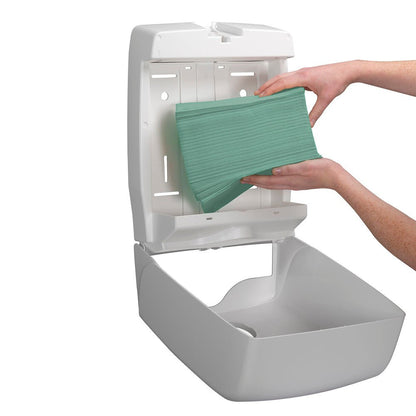 A person places a stack of Kimberly-Clark GmbH Hostess™ NATURA™ hand towels - zig-zag fold, small (23.00 cm x 25.00 cm) into an open white, wall-mounted paper towel dispenser.