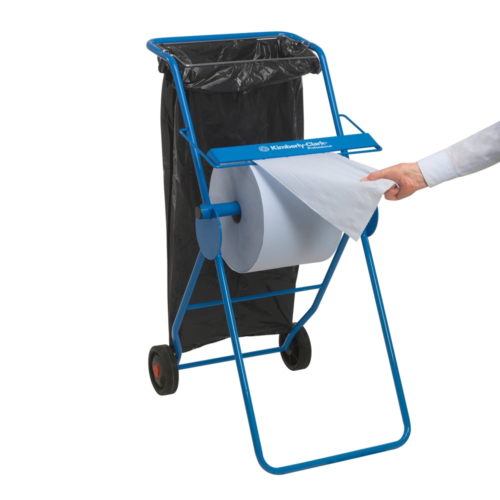 A hand pulls a WypAll® L20 paper wipe large roll from a large blue Kimberly-Clark dispenser on wheels with a black trash bag, ideal for maintenance work. 1 extra-wide roll x 1000 sheets, blue.