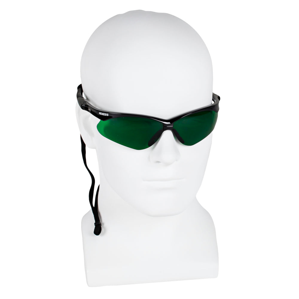 Ein weißer Schaufensterkopf trägt eine schwarz gerahmte Kimberly-Clark KleenGuard® V30 Nemesis™ Schutzbrille mit dunkelgrünen IRUV 3.0-Gläsern und einem schwarzen verstellbaren Band; 1 Karton enthält 12 Brillen.