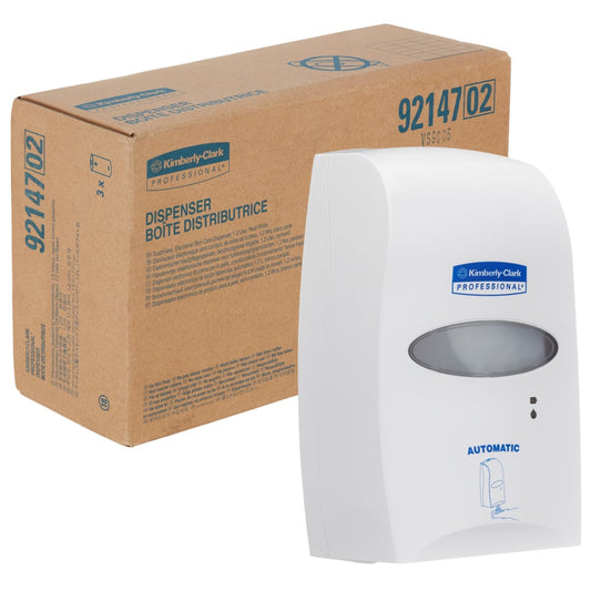 Ein weißer Kimberly-Clark Professional™ elektronischer Hautpflegespender (1,2 L, berührungslose Abgabe) der Kimberly-Clark GmbH ist vor einem braunen Karton mit der Aufschrift "DISPENSER BOITE DISTRIBUTRICE" und der Produktnummer 92147 abgebildet. Beide zeigen das Logo.