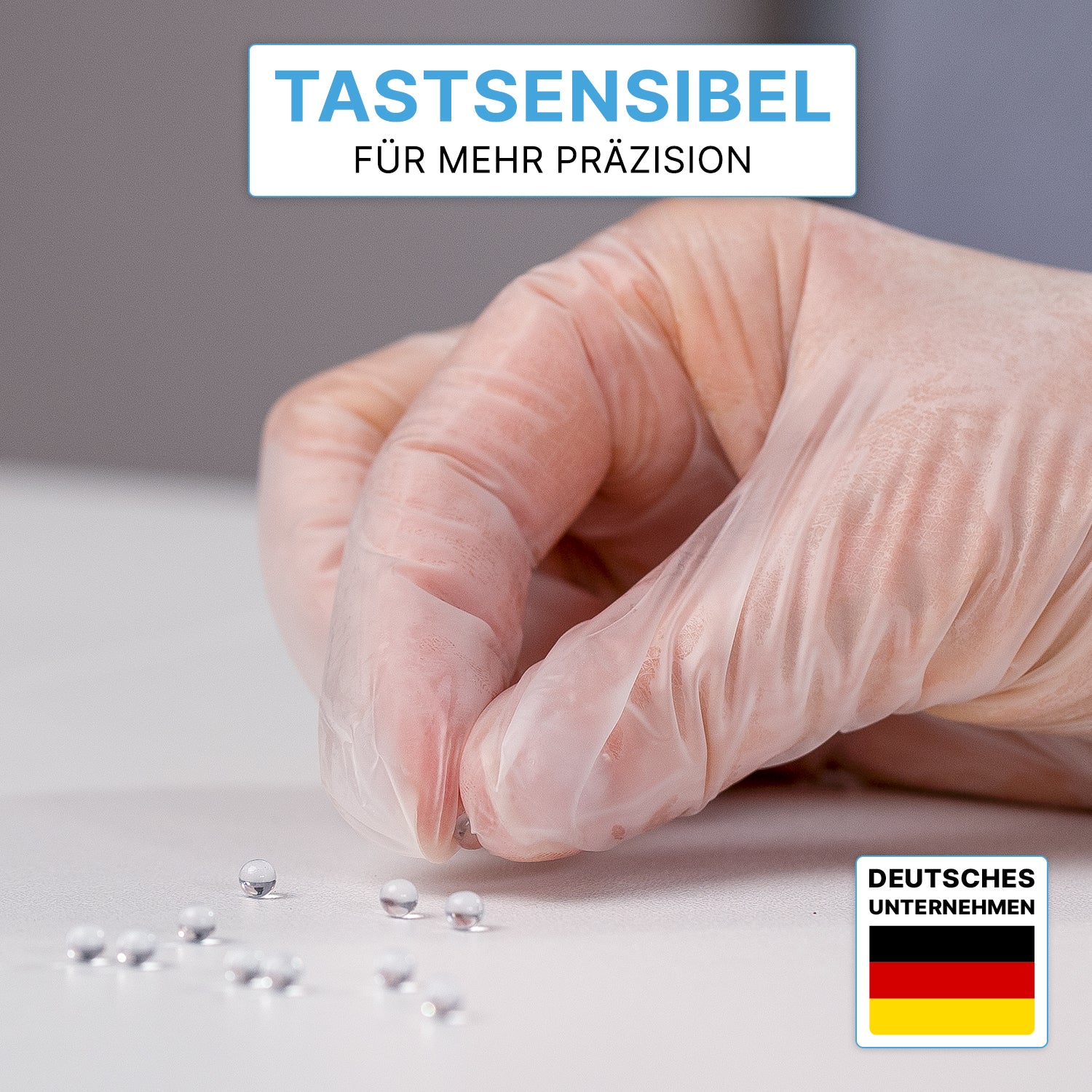 Eine Hand in ARNOMED VINYL PF Tastsensible Einmalhandschuhe von ARNOWA GmbH greift eine silberne Kugel von mehreren auf weißer Fläche. Oben steht: "Tastsensibel für mehr Präzision." Unten rechts ist eine Deutschland-Flagge zu sehen.