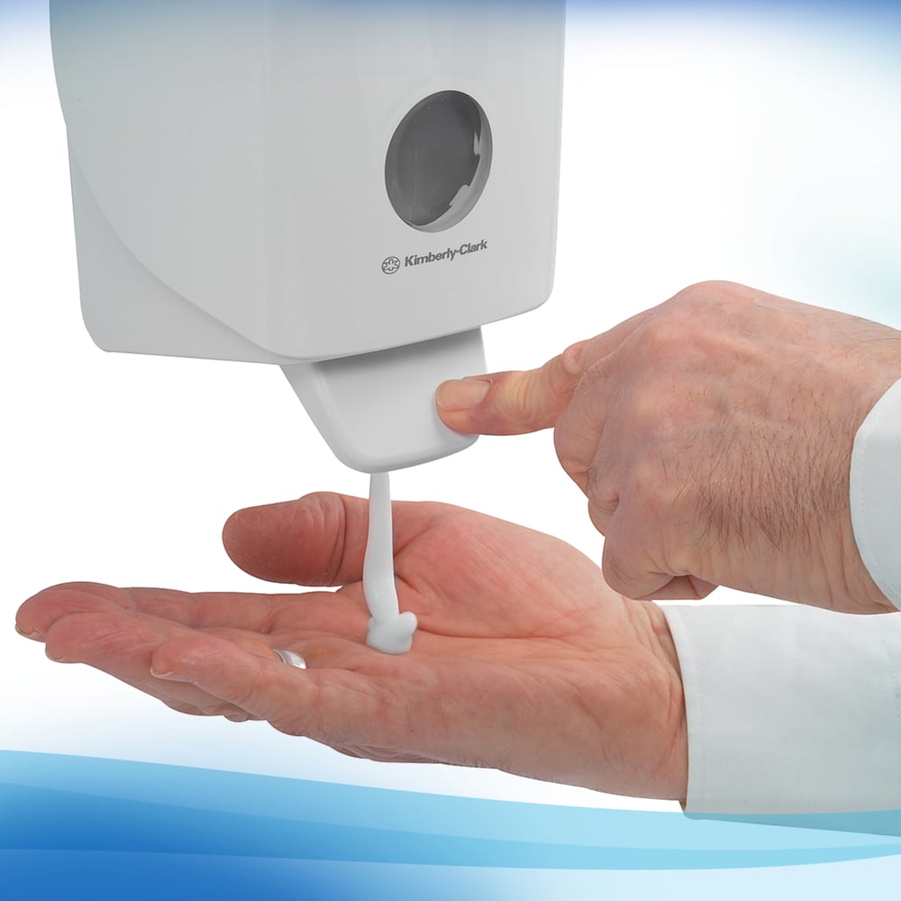 Eine Person in einem weißen langärmeligen Hemd drückt auf einen Kimberly-Clark Scott® Control™ 1L Schaum-Handreiniger Spender - ideal für den häufigen Gebrauch.