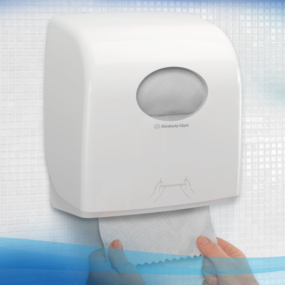 Eine Person zieht Scott® Essential™ Slimroll™ Handtücher (190 m x 19,8 cm) aus einem weißen Spender der Kimberly-Clark GmbH an einer gefliesten Wand; eine Illustration zeigt umweltfreundliche Händetrocknung mit diesen Papierhandtüchern.