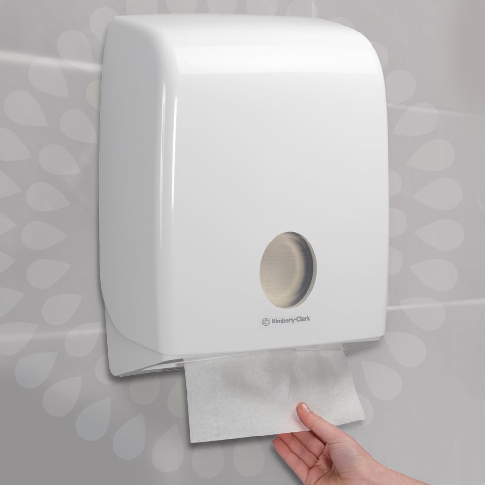 Ein weißer Wandspender der Kimberly-Clark GmbH spendet ein einzelnes Kleenex® Falthandtücher - Weiß/Groß, ideal für stark frequentierte Waschräume. Abgebildet: 15 Clips x 124 Blatt pro Karton (15 Packungen).