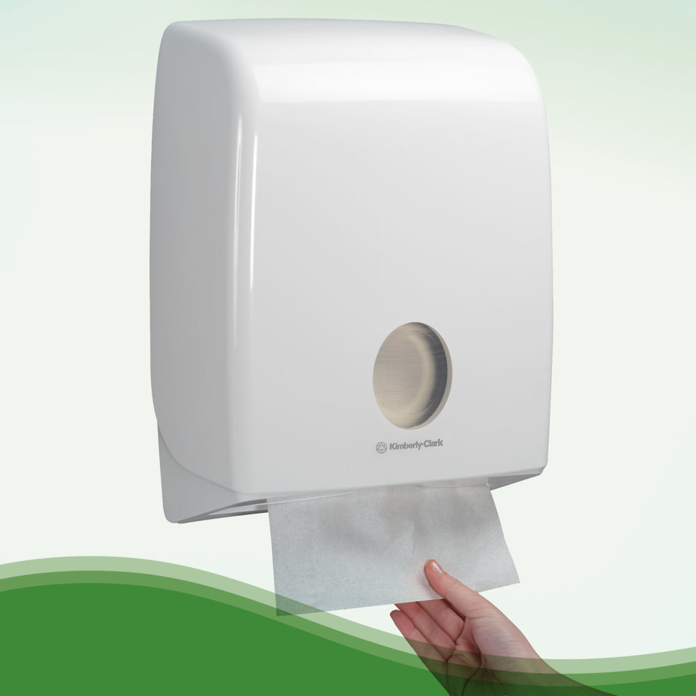 Eine Hand zieht Hostess™ NATURA™ Handtücher - Zick-Zack-Faltung, Klein (23 x 25 cm) von Kimberly-Clark GmbH aus einem weißen Wandspender mit rundem Sichtfenster auf der Vorderseite.