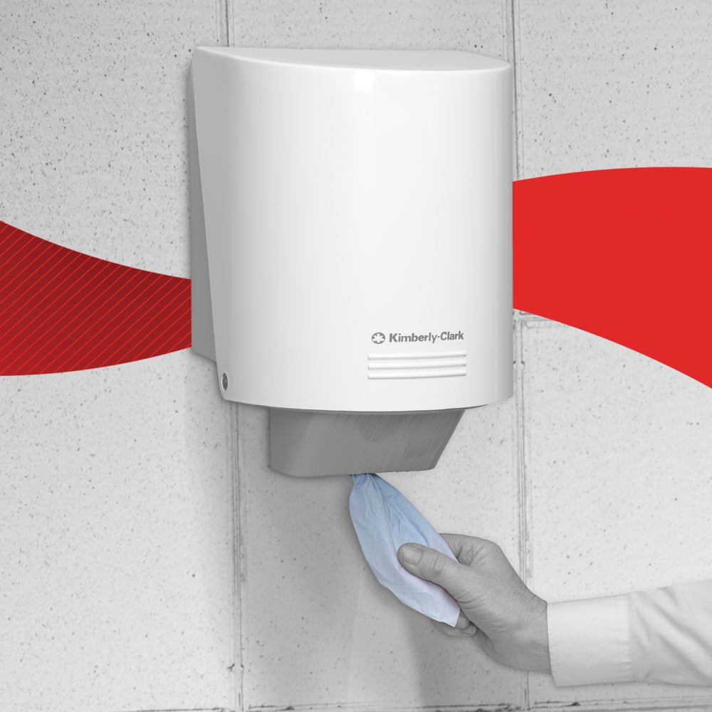 A hand pulls a blue WypAll® L20 2-ply paper wipe for maintenance work from Kimberly-Clark GmbH from a white wall dispenser with central dispensing, standing in front of a red, curved background.