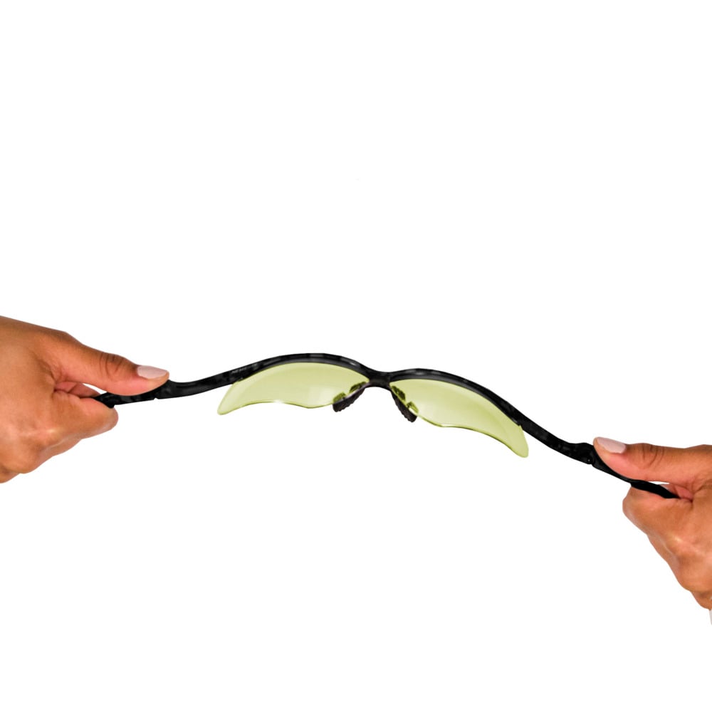 Zwei Hände ziehen an den Enden der KleenGuard® V30 Nemesis™ Schutzbrille - Caramel von Kimberly-Clark GmbH und biegen sie vor einem weißen Hintergrund nach außen, um ihre Haltbarkeit und ihren UV-Schutz zu demonstrieren. 1 Karton enthält 12 Gläser.
