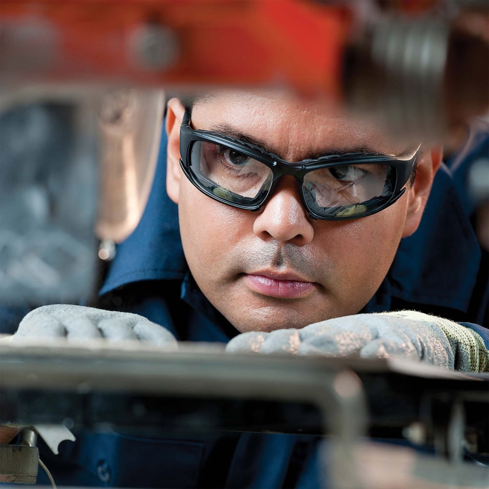 Eine Person, die die KleenGuard® V50 Calico™ Schutzbrille mit Beschlagfrei-Beschichtung und Handschuhe der Kimberly-Clark GmbH trägt, inspiziert Maschinen und sorgt für klare Sicht und optimale Sicherheit.