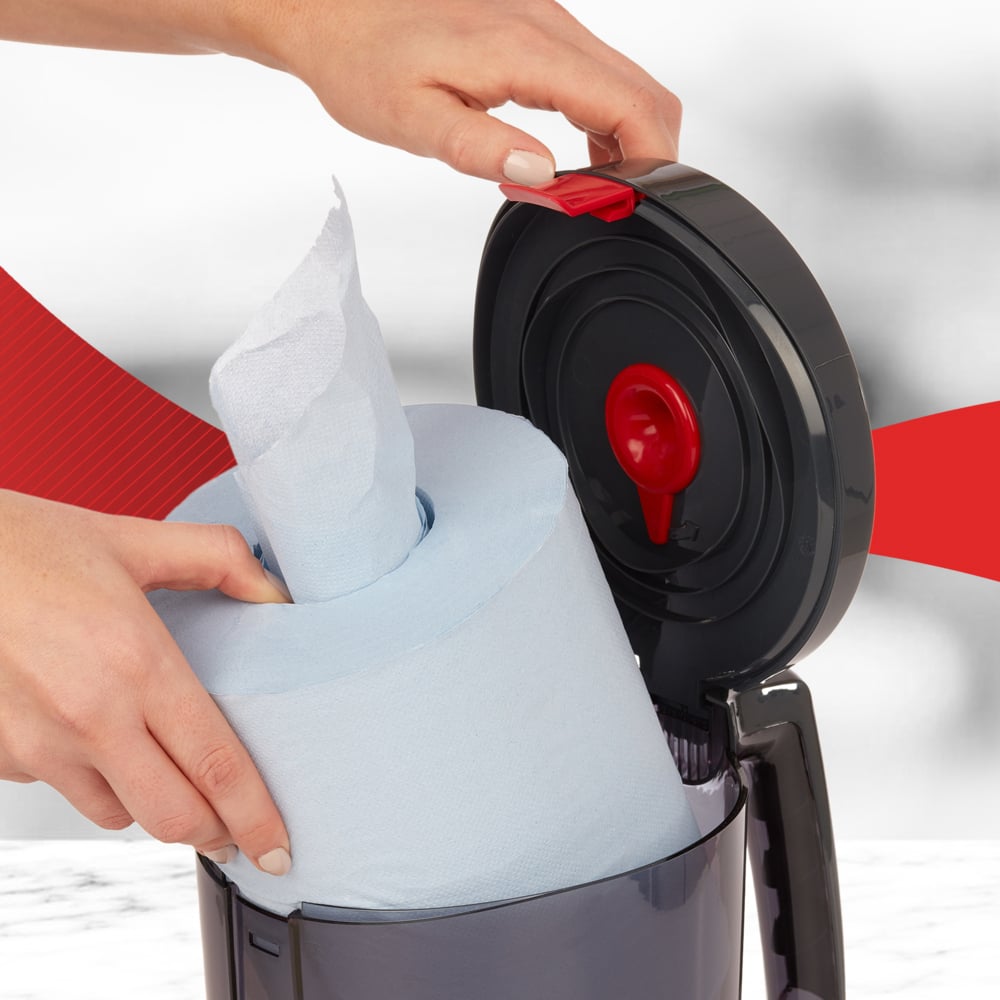 Ein Benutzer legt eine große blaue Rolle in den geöffneten WypAll® Reach™ Centrefeed Dispenser (Schwarz) von Kimberly-Clark GmbH ein, der den roten Auslösemechanismus zeigt - perfekt für den professionellen Einsatz.