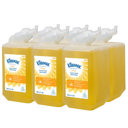 Sechs 1-Liter-Kassetten Kleenex® Botanics™ Luxury Foam Hand Wash (gelb) der Kimberly-Clark GmbH, jeweils mit weißer, gewinkelter Spenderdüse und orange-weißen Etiketten, sind in zwei Reihen angeordnet. Karton enthält 6 Kartuschen.