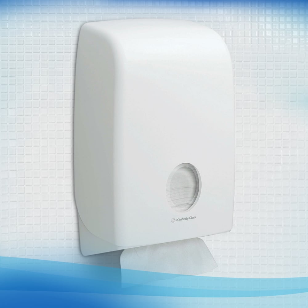 Ein weißer Scott® Control™-Spender der Kimberly-Clark GmbH ist an einer gefliesten Wand montiert. Ein Blatt herunterspülbare Falthandtücher (weiß) ist durch das runde Fenster sichtbar und zeigt den restlichen Vorrat im Inneren.