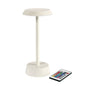 The NOUR Wireless LED Lamp in sand color by Duni GmbH is a modern table lamp with a round base and flat surface - elegant decor for your home, including a remote control with several colorful buttons.