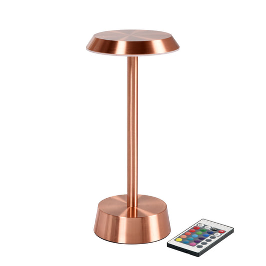 Eine roségoldene, kabellose NOUR LED-Lampe der Duni GmbH steht aufrecht mit einem runden Sockel und Schirm. Eine Fernbedienung mit farbigen Tasten ist neben dieser stilvollen LED-Lampe platziert (Packung: 1 Stück).