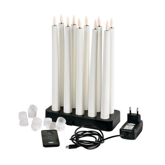 Das Duni GmbH LED Spitzkerzen 27,8cm, 10er, warmweiss Set kommt in einer Box mit schwarzer Ladestation, Netzteil, USB-Kabel, Fernbedienung und weißen Kerzenkappen - alles fein säuberlich auf einer weißen Fläche angeordnet.