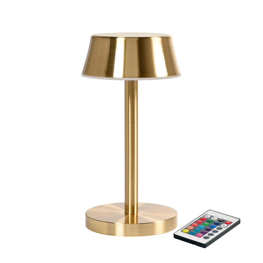 Die LED-Lampe, Nour Midi messing von Duni GmbH ist eine moderne goldfarbene Tischleuchte mit rundem Fuß und flachem Schirm, abgebildet neben einer Fernbedienung mit farbigen Tasten für energieeffiziente Beleuchtung. Die Packung enthält 1 Stück.