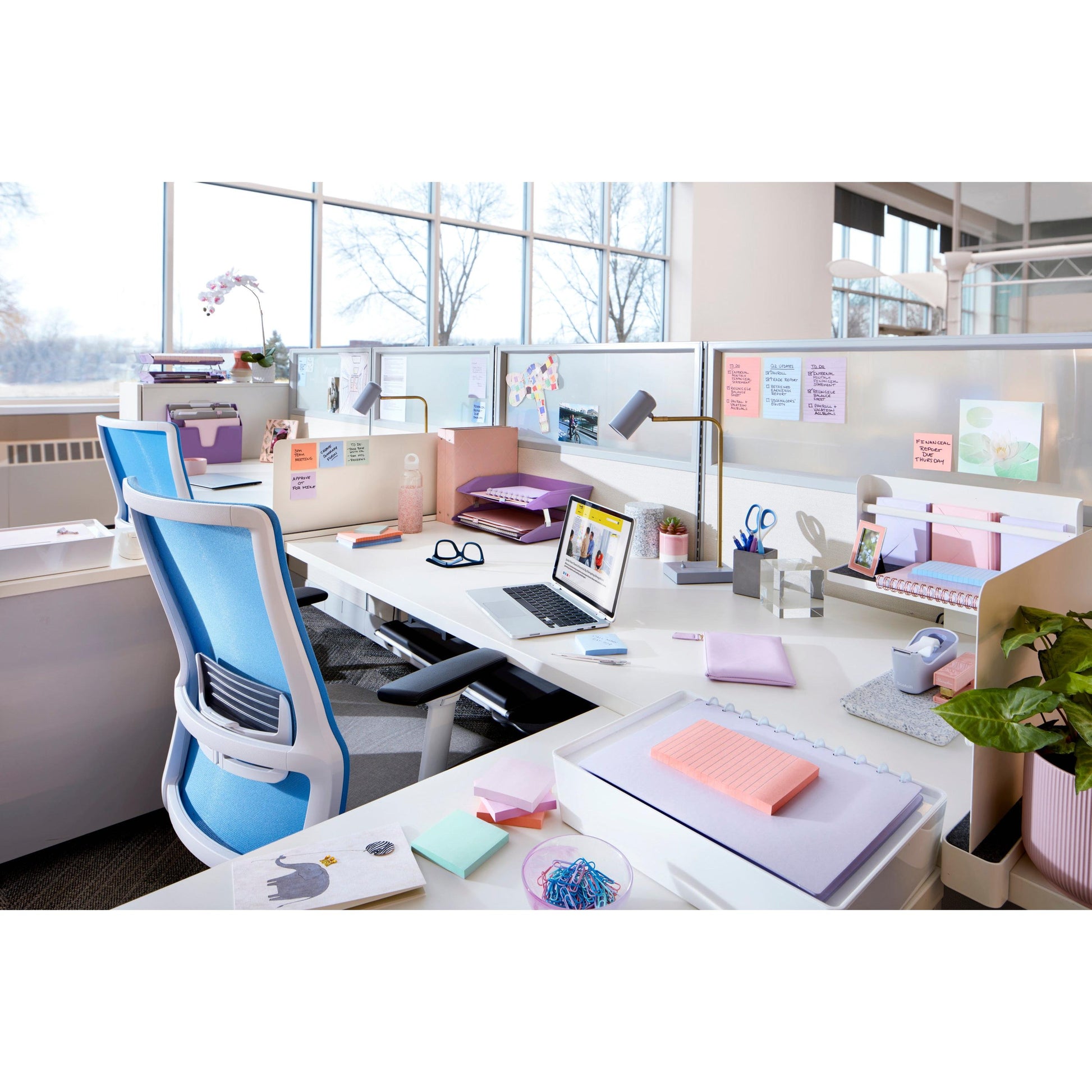 Ein moderner Büroarbeitsplatz mit weißen Schreibtischen, pastellfarbenen Schreibwaren, einem Laptop, Stühlen, Schreibtisch-Organizern, Pflanzen, großen Fenstern und Post-it® Super Sticky Notes (47,6x47,6mm, 90 Blatt/Block) von 3M Deutschland GmbH an den Trennwänden.