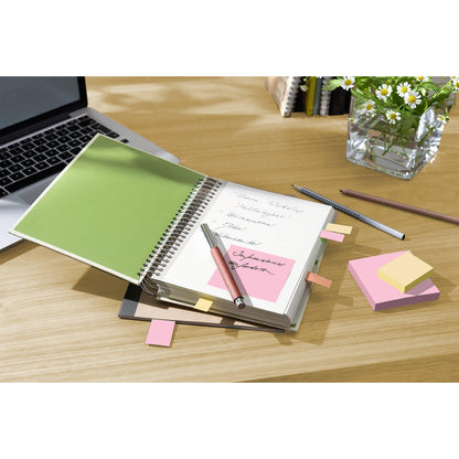 An open spiral notebook with handwritten notes lies on a desk next to a laptop, pens, a vase with white daisies, and Post-it® Recycling Notes (76 mm x 76 mm, 100 sheets/block, 100% PEFC) from 3M Deutschland GmbH. Inside the notebook are sticky notes and a pink note attached.