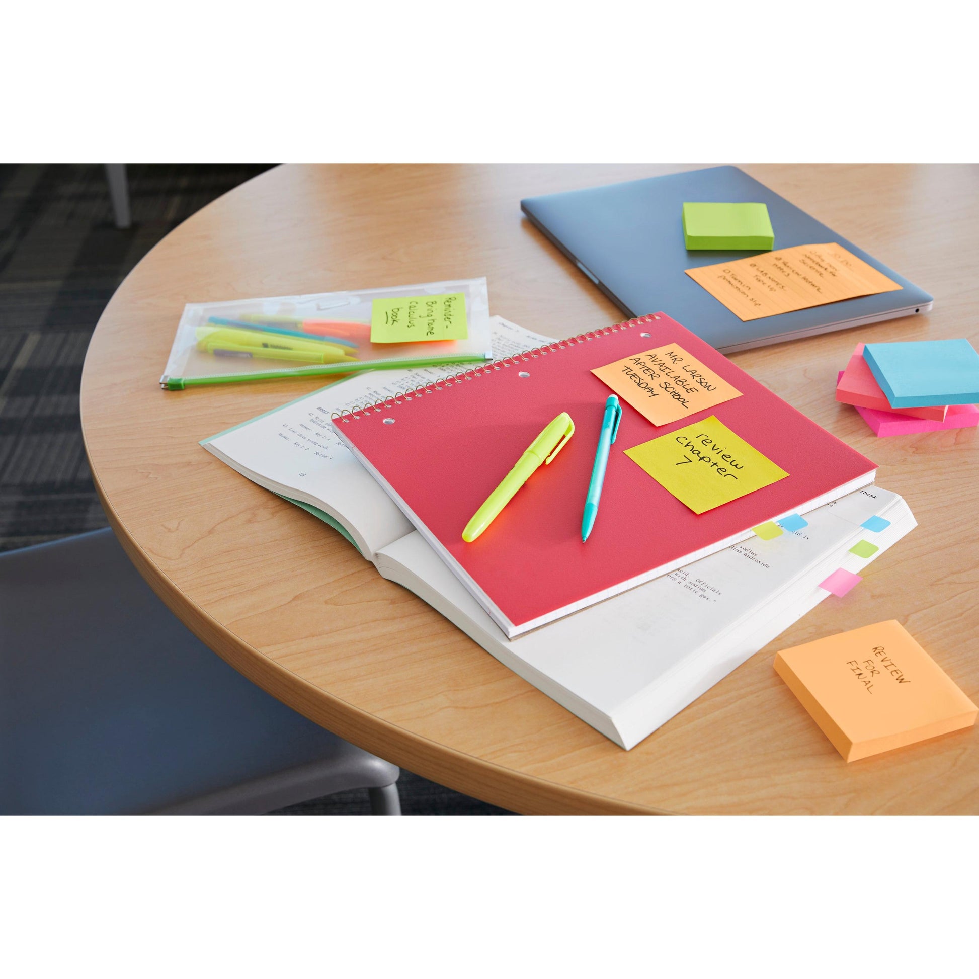 Auf einem runden Tisch liegen Notizbücher, Stifte, Textmarker, ein Federmäppchen, ein geschlossener Laptop und Stapel von Post-it® Super Sticky Notes (76 mm x 127 mm, 90 Blatt/Block, 100% PEFC) der 3M Deutschland GmbH; auf einigen Zetteln sind handschriftliche Erinnerungshinweise angebracht.