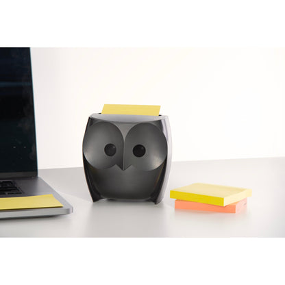 A 3M Post-it® Z-Notes Dispenser in owl shape, black, holds yellow Super Sticky Z-Notes. Next to it lie a closed laptop and a pack of yellow and pink Z-Notes (2 blocks of 45 sheets each) on a white desk.