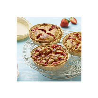 On a decorative metal stand are three small strawberry pies with lattice tops, in the background fresh strawberries and an empty PAPSTAR 50 baking molds "pure" brown from PAPSTAR GmbH, all on a blue background.