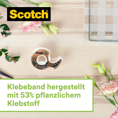 A Scotch™ stainless steel tape dispenser in silver with two rolls of Scotch® Magic™ tape (made from 66% plant-based adhesive, 19 mm x 13.9 m) from 3M Deutschland GmbH stands on light wood next to pink and yellow flowers.