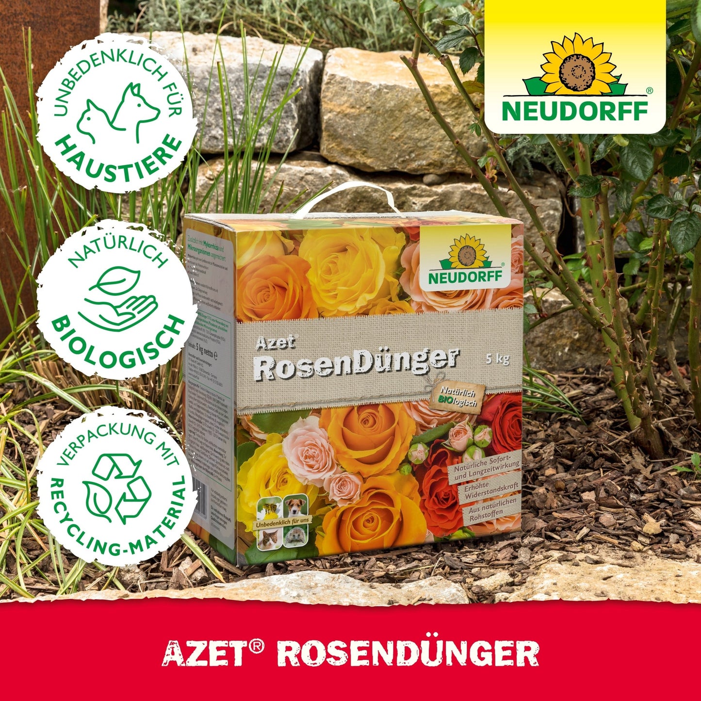 A box of Neudorff Shop Azet Rose Fertilizer lies in a garden between stones and plants. The packaging emphasizes pet safety, natural ingredients, and recyclable materials for blooming roses.
