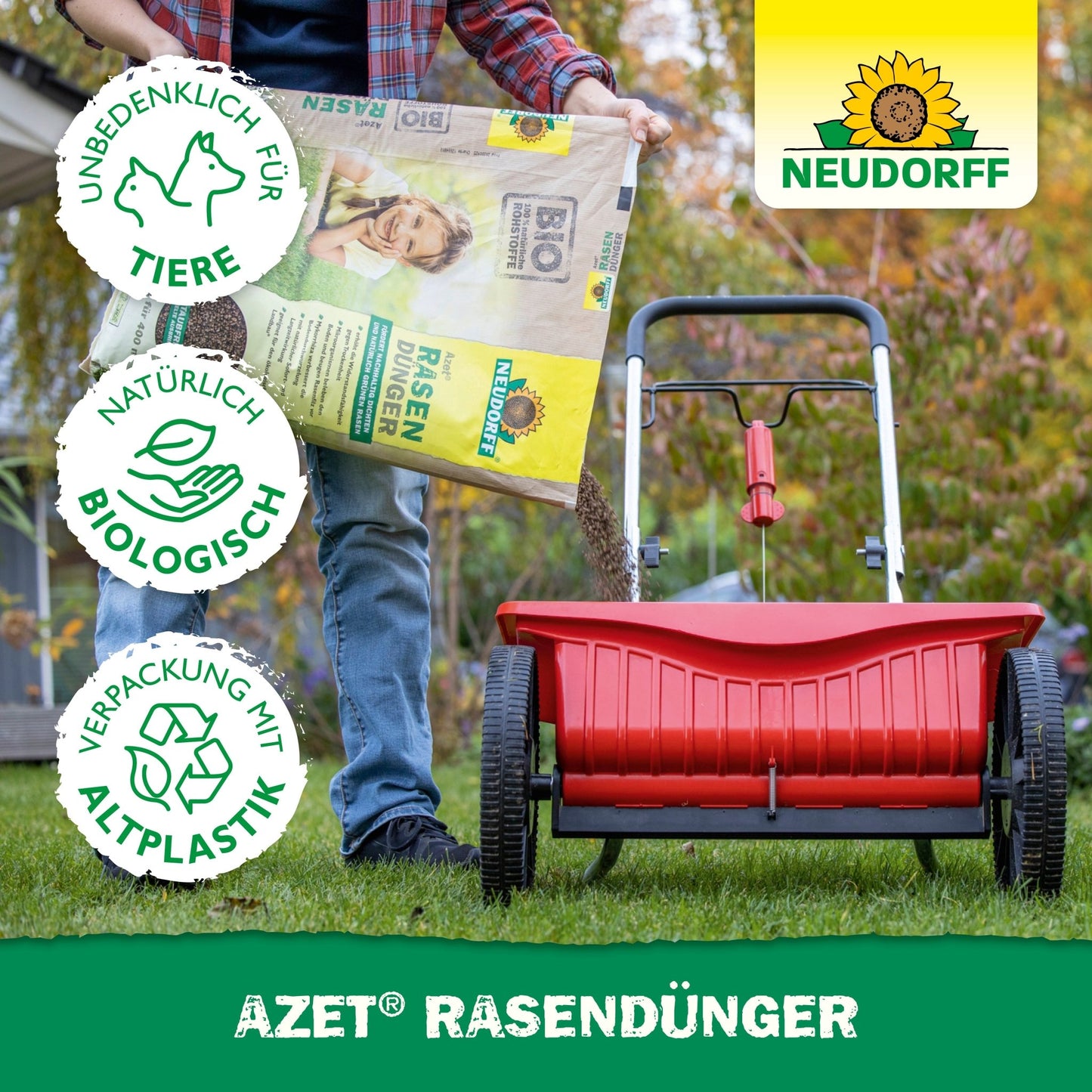 A person fills a red spreader with Neudorff Shop Azet Lawn Fertilizer 2.5-5 kg to promote dense lawn areas. Three symbols indicate it is pet-friendly, biologically natural, and made from recycled plastic. The Neudorff logo is visible.