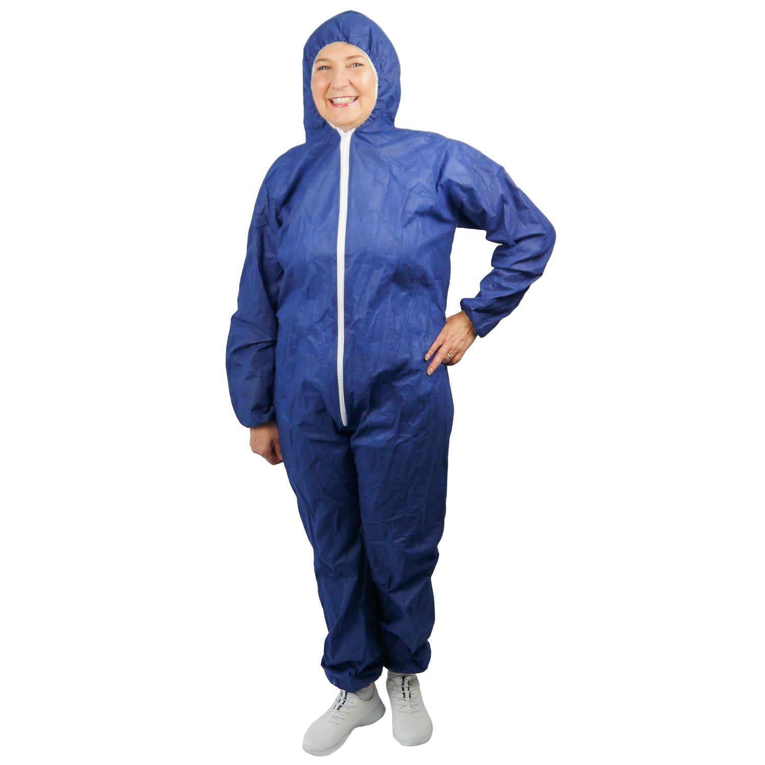 Eine Person steht vor der Kamera und trägt einen ARNOMED COVER PP-OVERALL BLUE Einmaloverall mit Kapuze aus PP-Vlies in Blau von ARNOWA GmbH, mit weißem Reißverschluss und weißen Schuhen, vor einem weißen Hintergrund.