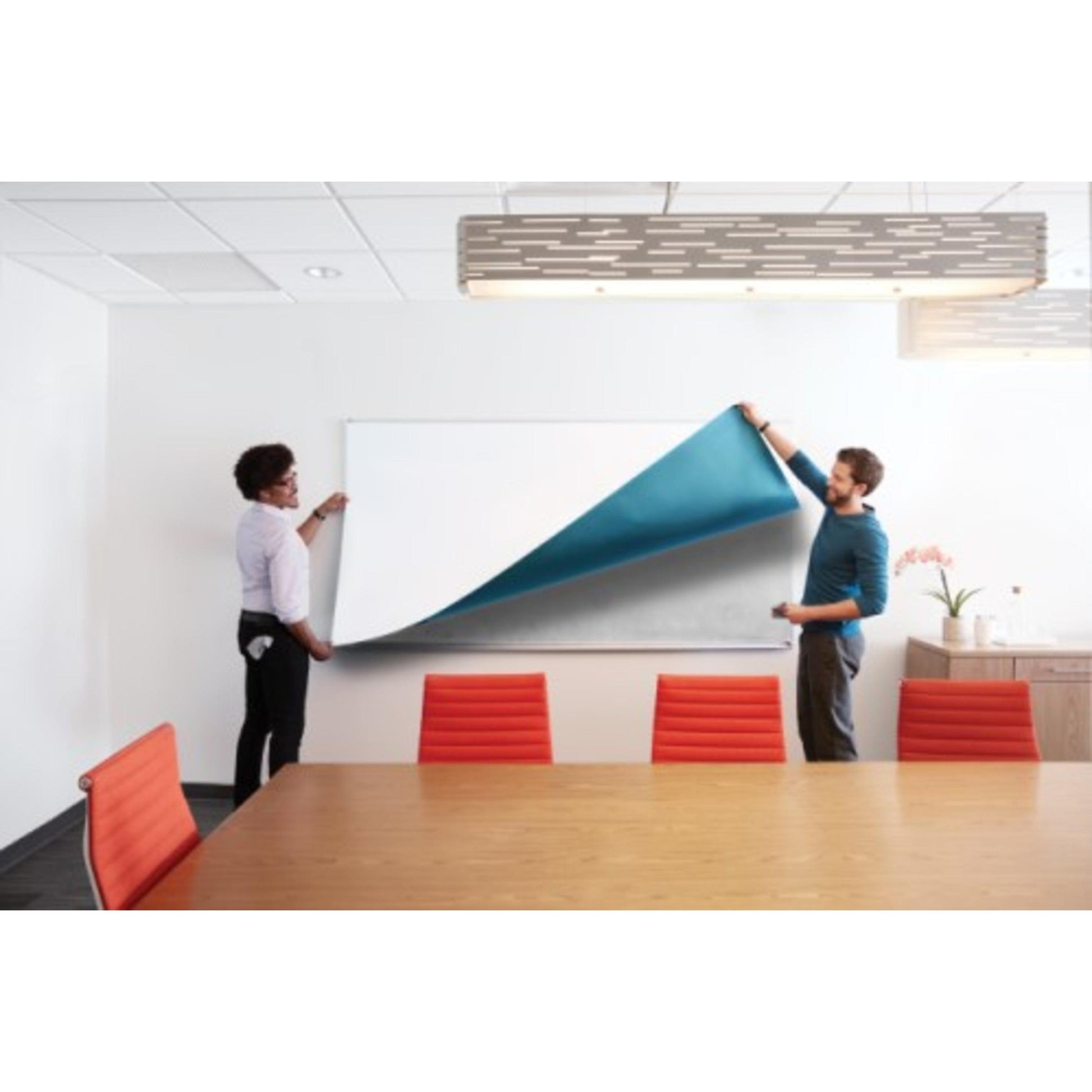 Zwei Personen bringen eine große Post-it® Easy Erase Whiteboard-Oberfläche (weiß) von 3M Deutschland GmbH über einem Whiteboard in einem Konferenzraum an. Der Raum ist mit roten Stühlen, einem Holztisch und einer modernen Deckenleuchte ausgestattet.