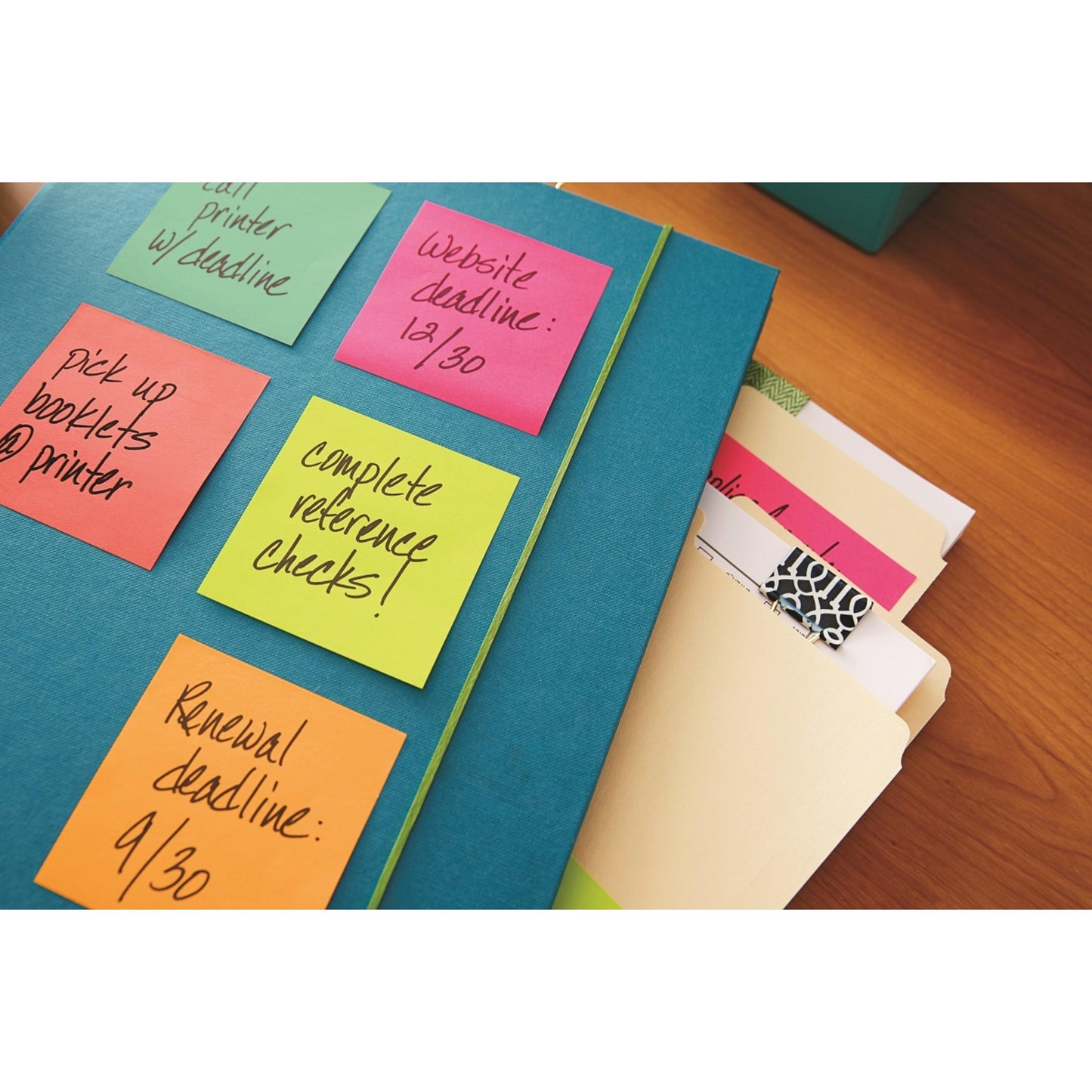 Eine blaue Mappe mit bunten 3M Deutschland GmbH Post-it® Notes Würfel, Ultra-Farben (76x76 mm, 450 Blatt/Block, PEFC-zertifiziert), in der Aufgaben aufgelistet sind, liegt neben Manila-Mappen und einem Notizblock auf einem Holztisch.