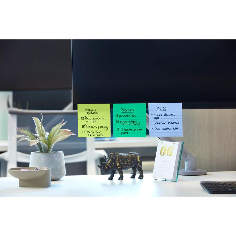 A computer monitor with Post-it® Super Sticky Notes (101 mm x 101 mm, 90 sheets, 100% PEFC) from 3M Deutschland GmbH, listing website updates and tasks to be done. Nearby: a potted plant, a black rhinoceros figure, a desk calendar with the date "06" and a bowl of paper clips.