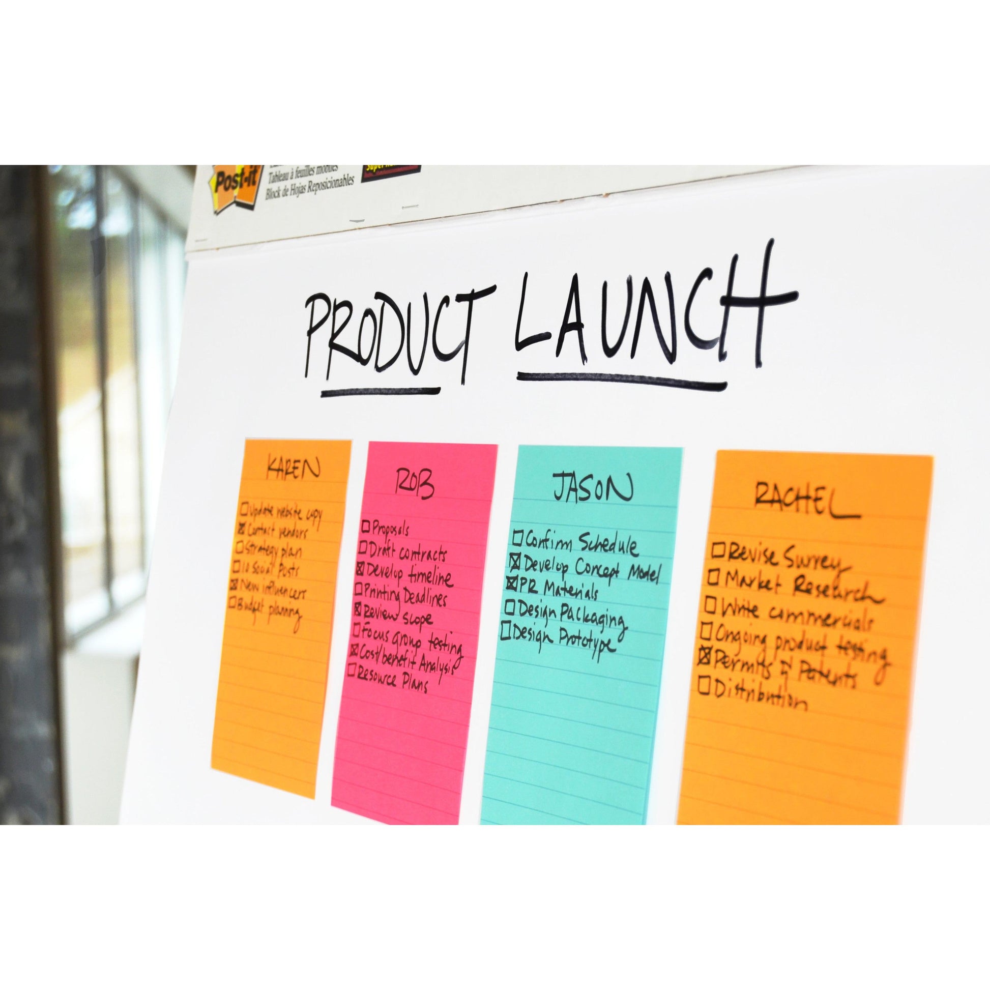 Auf einem Whiteboard mit der Aufschrift "Produkteinführung" befinden sich vier Spalten mit bunten, linierten Post-it® Super Sticky Notes (3M Deutschland GmbH, 101x152 mm, 90 Blatt/Block), auf denen jeweils Projektaufgaben für Karen, Riz, Jason und Rachel mit Kästchen markiert sind.