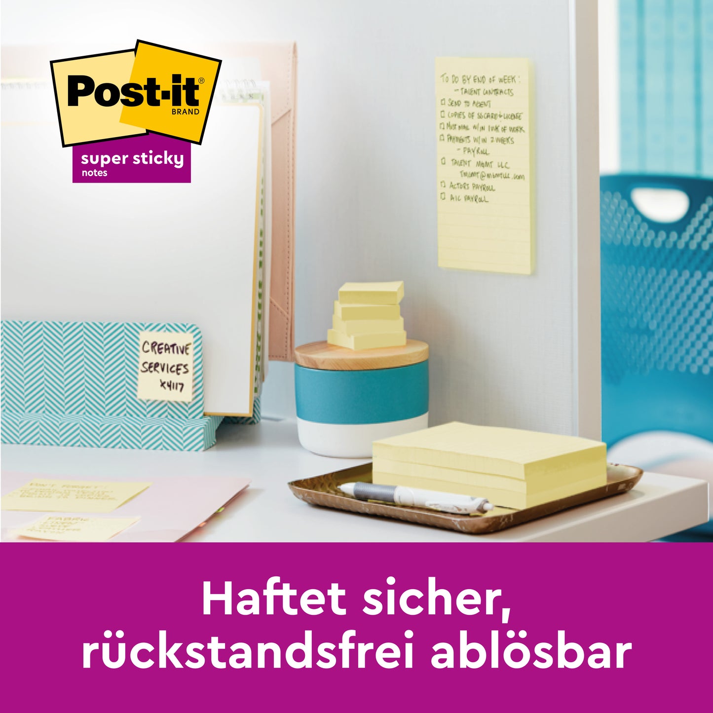 Ein aufgeräumter Schreibtisch mit 3M Deutschland GmbH Post-it® Super Sticky Notes, Gelb, 47,6 mm x 47,6 mm (PEFC-zertifiziert), befestigt an einer Trennwand. Deutscher Text: "Haftet sicher, rückstandsfrei ablösbar." Stapel von Notizen und Schreibwaren auf dem Schreibtisch.
