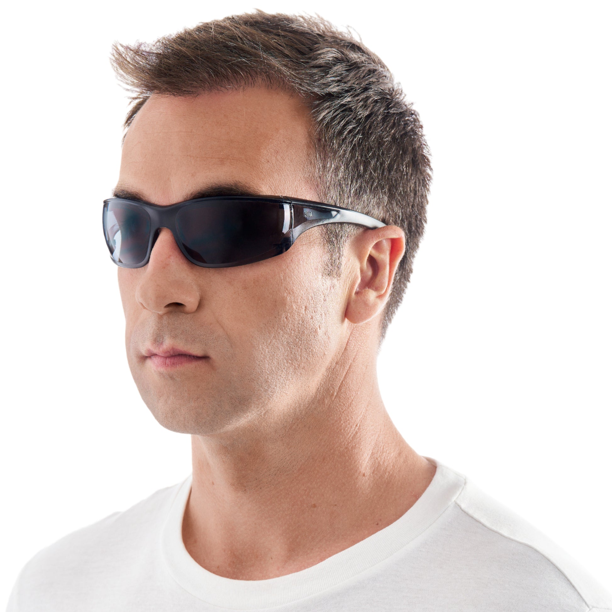Ein Mann, der ein weißes T-Shirt und 3M™ Virtua™ AP Schutzbrille, graues Glas von 3M Deutschland GmbH trägt, blickt leicht nach links vor einem schlichten weißen Hintergrund.