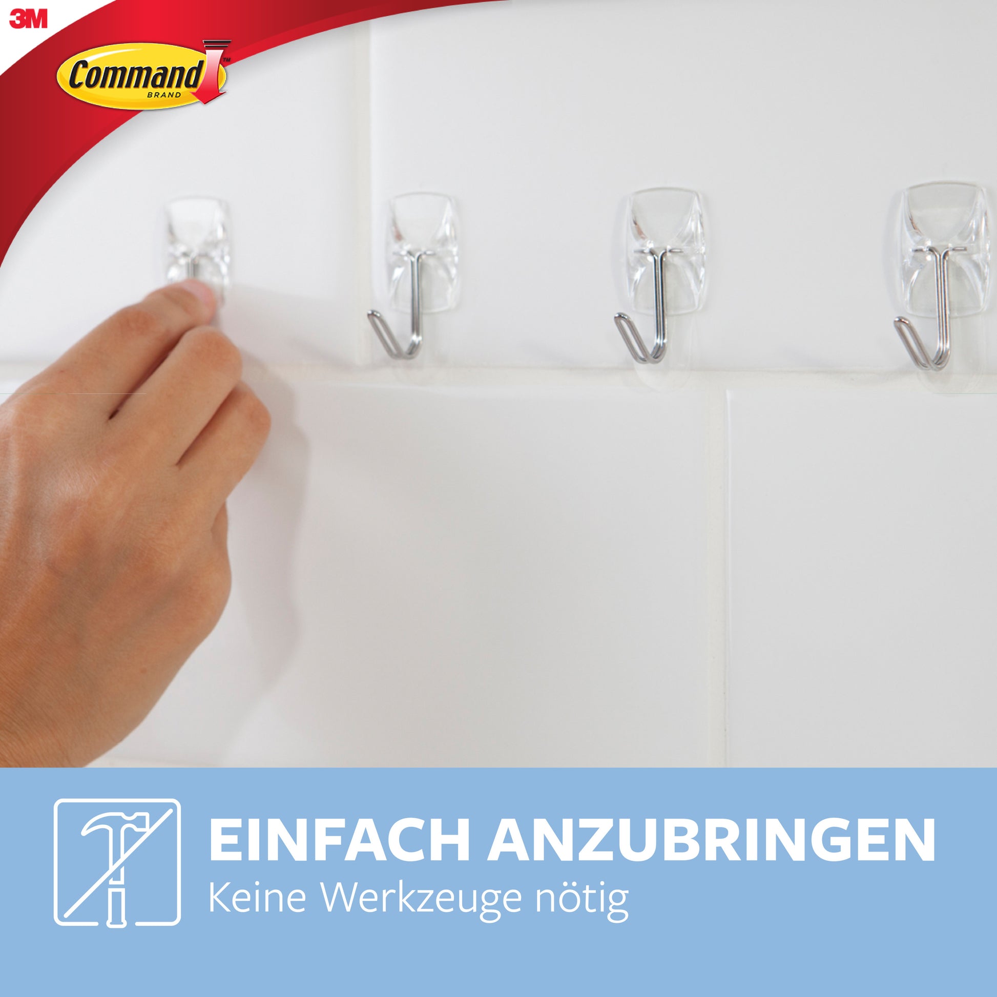 Eine Hand befestigt einen transparenten Command™ Drahthaken, klein, von 3M Deutschland GmbH, an einer weißen Fliesenwand neben drei bereits befestigten Haken. Text: "Einfach anzubringen. Keine Werkzeuge nötig.