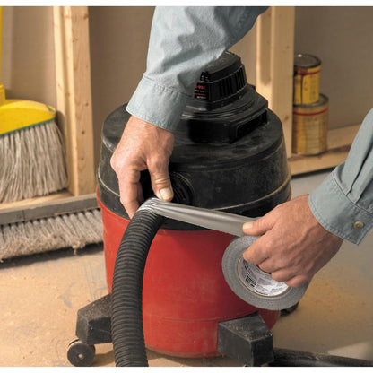 Someone wraps Scotch® Extremium™ Universal Adhesive Tape (3 m x 19 mm) from 3M Deutschland GmbH around the hose of a red-black workshop vacuum. A broom and paint cans lie on the dusty floor of a construction site.