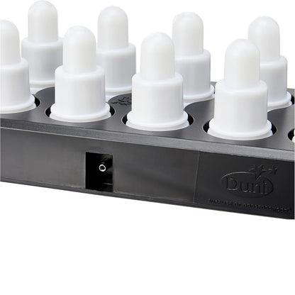Close-up of a black charging station for the Duni GmbH LED Set, Warm White & Multicolor - 12 Piece Color Changing Lights, with several white cylindrical charging ports with rounded caps and embossed Duni logo next to the socket.
