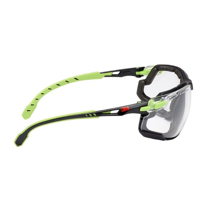 The 3M™ Solus™ Safety Glasses 1000 from 3M Deutschland GmbH have clear lenses, a black-green frame with adjustable green temples, and are equipped with a Scotchgard™ anti-fog coating and a foam gasket. The 3M logo is visible near the hinge.